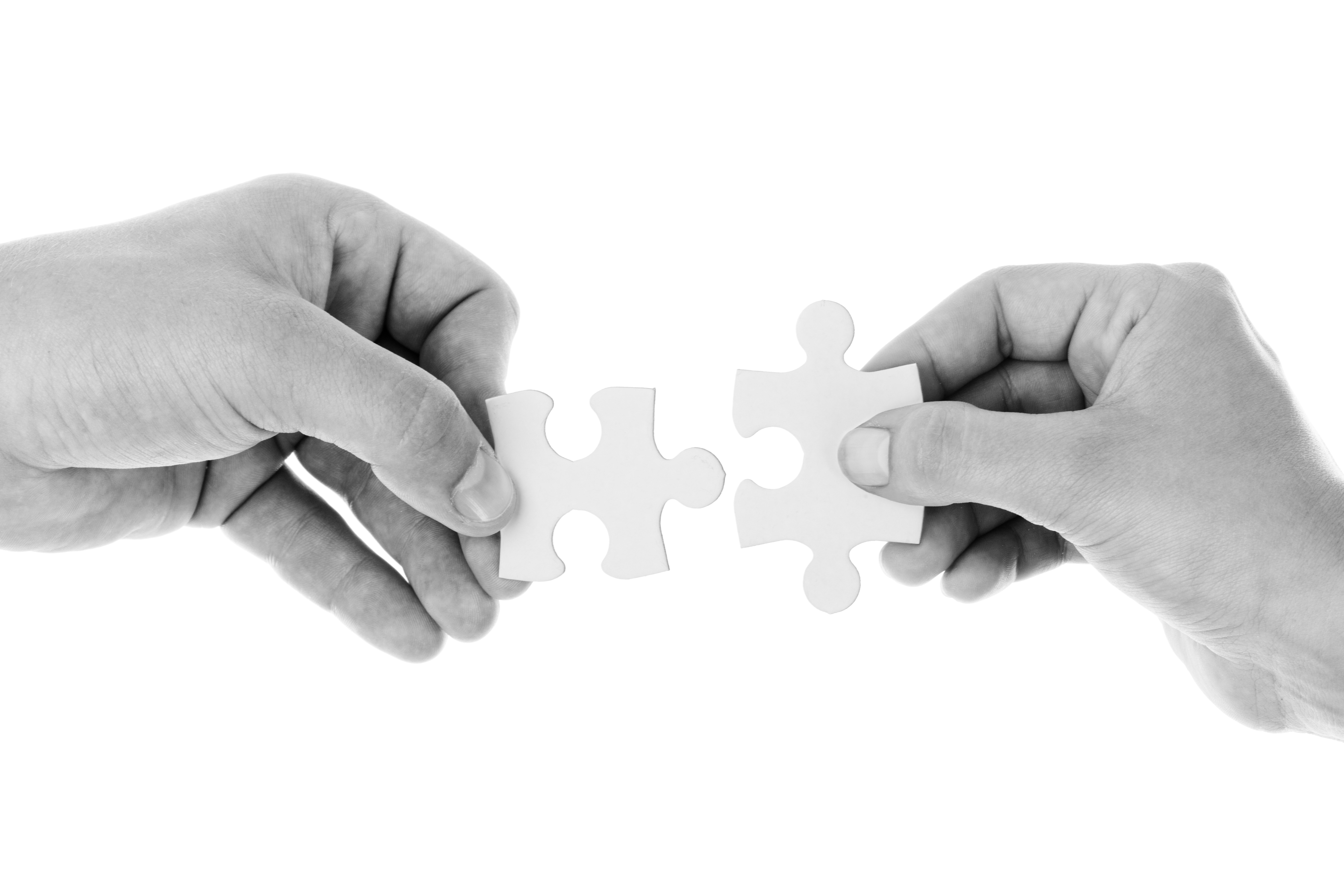 Two hands holding puzzle pieces about to connect them together